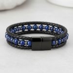 Gros plan d'un bracelet homme en cuir tressé noir avec perles de lapis-lazuli bleu sur fond pierre claire