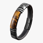 Poignet d'un homme portant un bracelet en cuir plat noir avec plaque centrale en œil de tigre et fermoir magnétique fond blanc