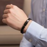 Poignet d'un homme portant un bracelet en cuir tressé noir avec perle centrale en acier noir et fermoir magnétique