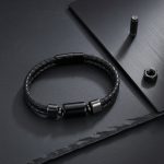 Bracelet homme en cuir tressé noir avec perle en acier noir présenté sur ardoise et métal brossé