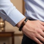 Poignet d'un homme portant un bracelet en cuir tressé noir avec perle centrale en agate marron et fermoir magnétique