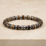 Gros plan d'un bracelet homme en rondelles d'œil de tigre et hématite argentée sur fond pierre claire