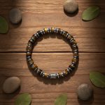 Bracelet homme en rondelles d'œil de tigre et hématite présenté sur bois avec éléments naturels