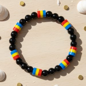 Bracelet en perles noires et perles tricolores bleu jaune rouge présenté sur bois clair