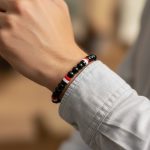 Poignet d'un homme portant un bracelet élastique en perles noires avec perles tricolores noir blanc rouge