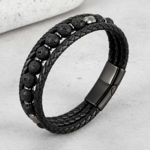 Gros plan d'un bracelet homme en cuir tressé noir avec perles de pierre de lave sur fond pierre claire