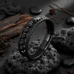 Bracelet homme en cuir tressé noir et pierre de lave présenté sur roche volcanique et bois