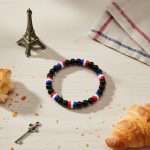 Bracelet en perles noires et perles tricolores bleu blanc rouge présenté sur bois clair