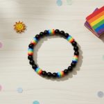 Bracelet en perles noires et perles arc-en-ciel multicolores présenté sur bois clair