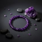 Bracelet en perles d'améthyste violette présenté sur ardoise avec druse d'améthyste brute