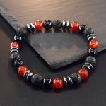 Gros plan d'un bracelet homme en agate rouge, onyx noir, pierre de lave et hématite sur fond ardoise