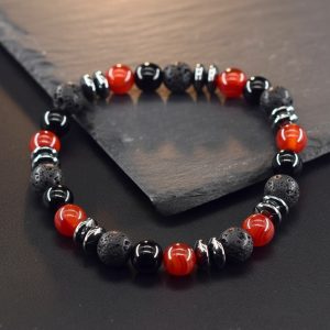 Gros plan d'un bracelet homme en agate rouge, onyx noir, pierre de lave et hématite sur fond ardoise
