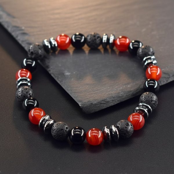 Gros plan d'un bracelet homme en agate rouge, onyx noir, pierre de lave et hématite sur fond ardoise