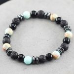 Gros plan d'un bracelet homme en amazonite turquoise, onyx noir, pierre de lave et hématite sur fond pierre claire