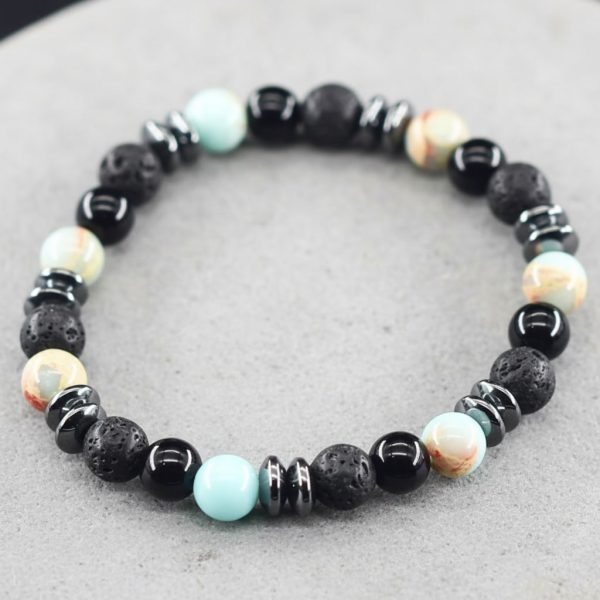 Gros plan d'un bracelet homme en amazonite turquoise, onyx noir, pierre de lave et hématite sur fond pierre claire