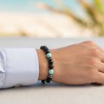 Poignet d'un homme portant un bracelet élastique en amazonite turquoise, onyx noir, pierre de lave et hématite
