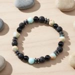 Bracelet homme en amazonite, onyx, pierre de lave et hématite présenté sur bois clair