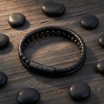 Bracelet homme en cuir tressé noir et perles de pierre de lave présenté sur bois foncé