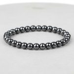 Gros plan d'un bracelet homme en perles d'hématite métallique brillante sur fond pierre claire avec 6 mm de taille de perle