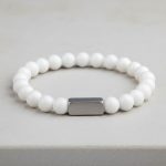 Poignet d'un homme portant un bracelet élastique en jade blanc pur avec barre centrale en acier brossé