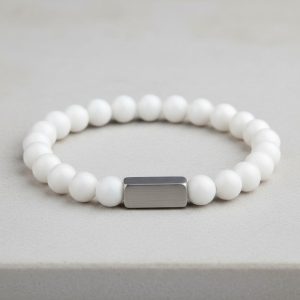 Poignet d'un homme portant un bracelet élastique en jade blanc pur avec barre centrale en acier brossé
