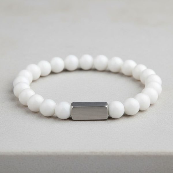 Poignet d'un homme portant un bracelet élastique en jade blanc pur avec barre centrale en acier brossé