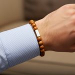 Poignet d'un homme portant un bracelet élastique en jaspe bois brun avec barre centrale en acier brossé