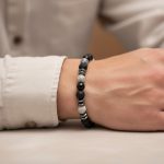 Poignet d'un homme portant un bracelet élastique en jaspe paysage gris, onyx noir, pierre de lave et hématite
