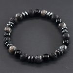 Gros plan d'un bracelet homme en larvikite grise, onyx noir, pierre de lave et hématite sur fond ardoise