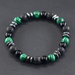 Gros plan d'un bracelet homme en malachite verte, onyx noir, pierre de lave et hématite sur fond ardoise