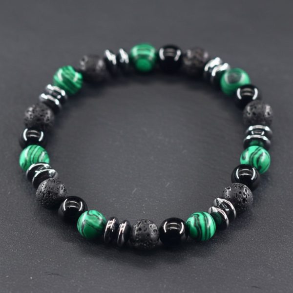 Gros plan d'un bracelet homme en malachite verte, onyx noir, pierre de lave et hématite sur fond ardoise