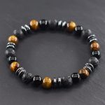 Gros plan d'un bracelet homme en œil de tigre, onyx noir, pierre de lave et hématite sur fond ardoise