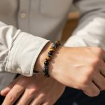 Poignet d'un homme portant un bracelet élastique en œil de tigre, onyx noir, pierre de lave et hématite