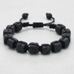 Gros plan d'un bracelet homme en cubes de pierre de lave tissé macramé sur cordon ajustable