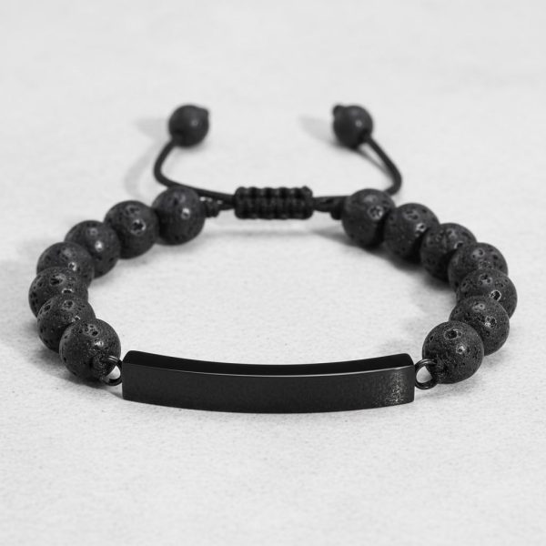 Gros plan d'un bracelet homme en perles de pierre de lave avec plaque en acier noir sur cordon ajustable