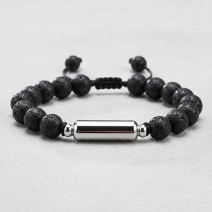 Gros plan d'un bracelet homme en perles de pierre de lave avec tube en acier argenté sur cordon ajustable