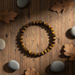 Bracelet en perles d'œil de tigre doré de 6 mm présenté sur bois avec éléments naturels