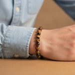 Poignet d'un homme portant un bracelet élastique en perles d'œil de tigre doré de 8 mm