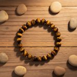 Bracelet en perles d'œil de tigre doré de 8 mm présenté sur bois avec éléments naturels