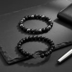 Ensemble de deux bracelets homme en onyx noir, pierre de lave, hématite et croix présenté sur ardoise
