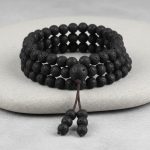 Gros plan d'un mala tibétain 108 perles en pierre de lave avec perle guru et pompon sur fond pierre claire