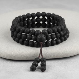 Gros plan d'un mala tibétain 108 perles en pierre de lave avec perle guru et pompon sur fond pierre claire