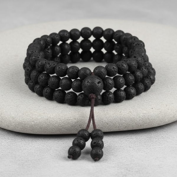 Gros plan d'un mala tibétain 108 perles en pierre de lave avec perle guru et pompon sur fond pierre claire