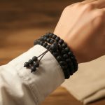 Poignet d'un homme portant un mala tibétain 108 perles en pierre de lave enroulé plusieurs fois