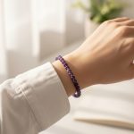 Poignet portant un bracelet élastique fin en perles d'améthyste violette de 6 mm