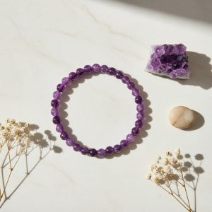 Bracelet en perles d'améthyste violette de 6 mm présenté sur pierre claire avec cristal d'améthyste