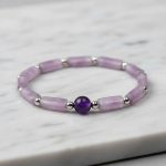 Gros plan d'un bracelet en tubes d'améthyste lavande, perles acier et améthyste foncée sur fond clair