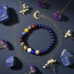 Bracelet système solaire lapis-lazuli perles planètes flat lay fond sombre étoiles dorées