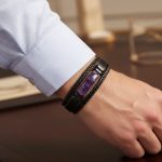 Poignet d'un homme portant un bracelet en cuir noir multi-rangs avec barre centrale en améthyste violette et fermoir magnétique