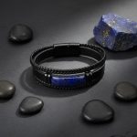 Bracelet homme en cuir noir et barre de lapis-lazuli présenté sur ardoise avec lapis-lazuli brut